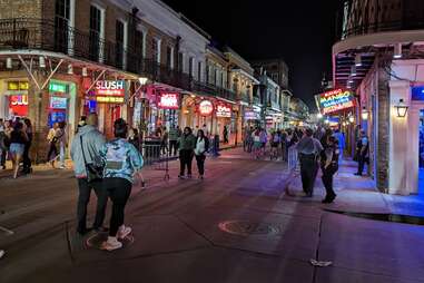 bars on bourbon street in the french quarter of new orleans at night with lots of neon signs