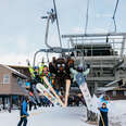 a mammoth, skiers, and snowboarders on a chairlift at mammoth mountain for opening day