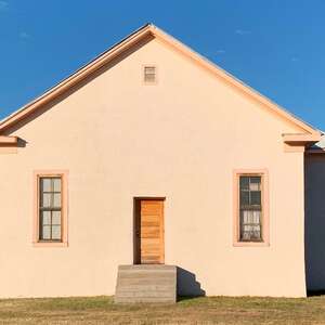 a peach adobe house with wooden slats that was once a schoolhouse