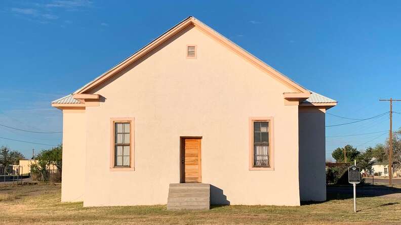 a peach adobe house with wooden slats that was once a schoolhouse